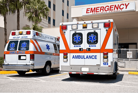 Photo of two ambulances parked in front of the emergency room door at a hospital